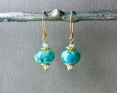 "⇩CLICK BELOW FOR DETAILS⇩ ✦These hand blown turquoise blue green lampwork bead earrings are magnificent. Each handmade lampwork abstract glass borosilicate bead, measures 10mm x 14mm and is filled with gorgeous blues and turquoise to create a stunning look. The beads are adorned with beautiful gold daisy spacers and wire wrapped to sturdy 18k gold vermeil round hook ear wires. Earring length is about 1.25 inches. ✦Your jewelry will be packaged in a beautiful and reusable organza bag. All items Lampwork Bead Earrings, Turquoise Bead Earrings, Gold Statement Earrings, Jewelry Beaded, Turquoise Glass, Mom Jewelry, Jewelry Card, Rose Gold Jewelry, Small Earrings