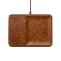 a square brown leather tray with a handle on the top and an empty plate underneath it