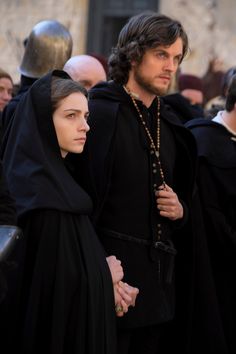 a man and woman dressed in black standing next to each other with people behind them