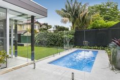 an empty swimming pool in the middle of a backyard with trees and bushes around it