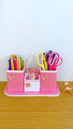 a pink desk set with scissors, pens and pencils in it on a wooden table