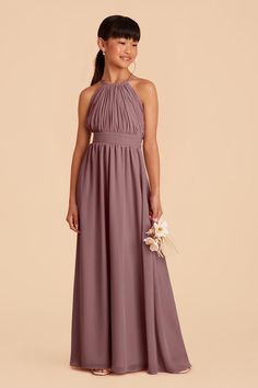 a woman in a long purple bridesmaid dress standing with her hands on her hips