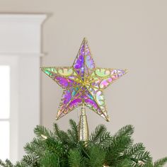 an ornament on top of a christmas tree in the shape of a star