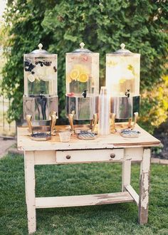 an old table with three glass vases on it and some lemon slices in them