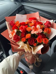 a bouquet of red and orange roses in a car