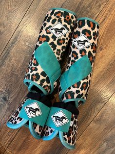 two pairs of leopard print boots with blue and black bows on the toes, sitting on top of a wooden floor