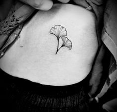 a black and white photo of a woman's stomach with a flower tattoo on it