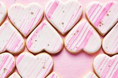 heart shaped cookies with pink and white icing arranged in the shape of hearts on a pink background