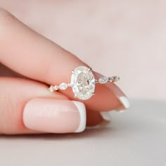 a woman's hand holding an oval diamond ring