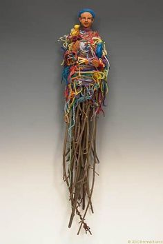 a sculpture of a woman holding a bird on top of a pile of sticks and wires