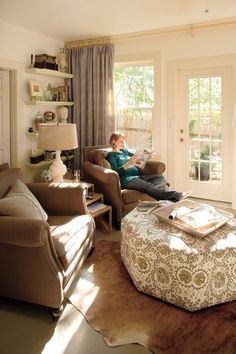 a person sitting on a couch in a living room next to a table and chair