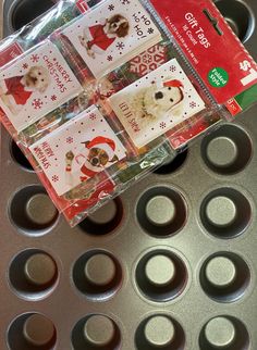 a muffin pan filled with cupcake tins and christmas stickers on top