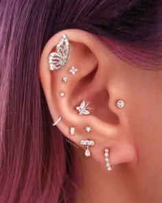 a woman with purple hair wearing ear piercings and butterfly wings on her left side