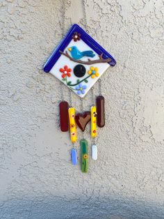 a colorful clock hanging from the side of a wall with flowers and birds on it