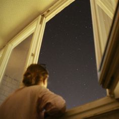 a woman looking out the window at the stars