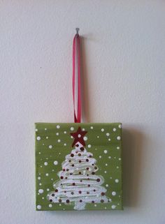 a christmas ornament hanging on the wall with a red and white ribbon around it