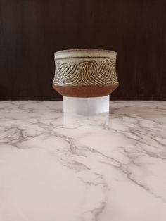 a white and brown vase sitting on top of a marble counter