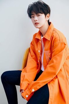 a man sitting on top of a chair wearing an orange jacket