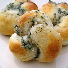 three rolls covered in cheese and herbs on a plate