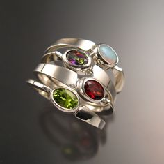 "Set of four Sterling Silver asymmetrical rings with your choice of 4mm x 6mm oval natural birthstones.(restrictions apply) Four rings are about 8-9mm wide at the bottom and 15 - 16mm at the top. Mixed shapes and premium stones are extra. Specify size and stone preference in a \"note to seller\" at check-out. It is always best to send a note to work out the details before ordering." Asymmetrical Rings, Mothers Birthstone Ring, Asymmetrical Ring, Birthstone Ring Mothers, Birthstone Stacking Rings, Rings Handmade, Mother Rings, Gold Rings Fashion, Three Rings