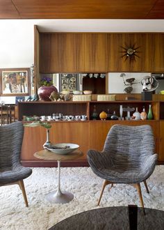 a living room with two chairs and a table in front of a bookshelf