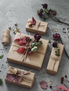 three wrapped gift boxes with dried flowers and twine on the table next to scissors