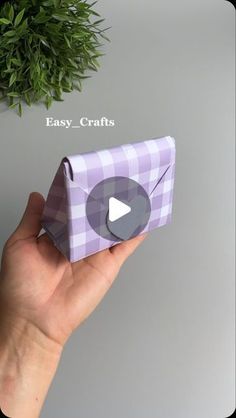 a hand holding an origami box with a play button