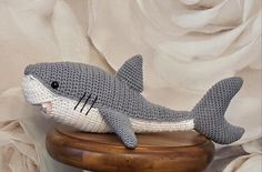 a crocheted stuffed shark sitting on top of a wooden stool