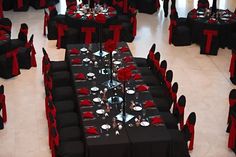 a room filled with black tables covered in red and white table cloths, silverware and place settings