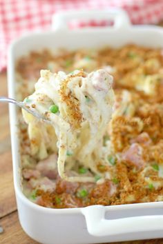 a spoonful of mashed potatoes with ham and peas in a casserole dish