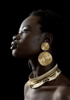 an african woman wearing gold jewelry and earrings