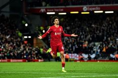 a soccer player is running on the field with his arms out and one foot in the air