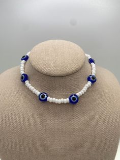 -Blue evil eye beaded necklace with white Czech beads. -This Necklace is simple and yet so fun!  -It's perfect for stacking or wearing alone. It's your choice! -Whether you're going for a casual or a dressy look, this set will add the perfect final touch to all your looks! CARE INSTRUCTIONS TIPS: -Avoid strong chemicals and water to keep them looking like new for much longer -Store away from other jewelry to avoid tangling or scratches -Clean with a soft, dry cloth SHIPPING: -  We are dedicated to ship your orders as soon as a possible.  -Most orders will be shipped out within the same day the order was placed.  -  Feel free to contact us if you need to rush your order, we are happy to accommodate.  -Free shipping on orders over $35 -Feel free to contact us for more details.   ADDITIONAL I White Beaded Round Evil Eye Bracelet, White Evil Eye Bracelet With Round Beads, Adjustable White Beaded Necklace With Evil Eye, White Round Beaded Evil Eye Bracelet, White Evil Eye Jewelry Gift, White Evil Eye Bracelet With Colorful Round Beads, Handmade White Evil Eye Bracelet Gift, White Evil Eye Bracelet Gift, White Round Beaded Necklaces For Spiritual Occasions