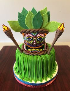 a cake decorated with green icing and decorations on top of a wooden table in front of a white wall