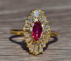 The Dorum Exquisite Signed Ruby & Diamond Navette Ring in Yellow Gold. The center is set with a 0.58 carat Marquise Brilliant cut no heat natural vivid red ruby. Surrounding the center in a ballerina type halo is a row of tapered baguette cut diamonds with a total weight by measurement of 0.50 carats. The ring is crafted in 18 karat yellow gold and is currently a size 6 yet can be adjusted to any finger size. Each piece has been hand selected and meticulously identified and graded by a Gradu Vintage Ruby Ring In Marquise Cut, Luxury Marquise Cut Ruby Ring For Gift, Luxury Vintage Marquise Ruby Ring, Luxury Marquise Cut Ruby Ring In Yellow Gold, Vintage Marquise Ruby Ring Gift, Navette Ring, Rings Ruby, Cute Engagement Rings, Gold Rings Fashion