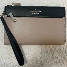 Kate Spade, Medium Leather Wristlet(Warm Beige With Black Accent). 8 Inches Long By 5 Inches High By 1 Inch Width. Inside Has Six Card Slots And Black Jacquard Spade Lining. Gold Tone Hardware. Outside Front Zipper Pocket. Handle Can Clip Off. One Divider. Divider Has The Card Slots. Never Used. Received As A Gift. I Am Not Sure Exactly On The Style But It Seems To Be The Kate Spade Saffiano Leather Wristlet On Amazon For $70. I Cannot Read The Small White Tag Inside Bottom Of The Wristlet. Elegant Beige Clutch Wristlet, Elegant Beige Clutch With Wrist Strap, Cream Wristlet With Zipper Closure For Travel, Kate Spade Beige Wallet For Everyday Use, Kate Spade Beige Wallets For Everyday Use, Elegant Cream Wristlet With Zipper Closure, Elegant Beige Wristlet For Travel, Beige Wristlet With Zipper Closure For Travel, Beige Travel Wristlet With Wrist Strap