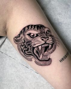 a black and white tiger tattoo on the right arm, with its mouth open showing