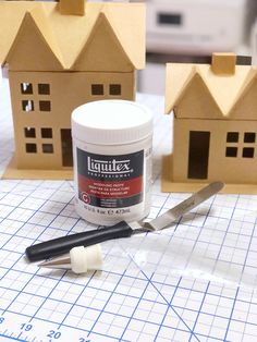 some crafting supplies sitting on top of a cutting board next to small model houses