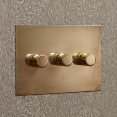 three knobs are on the side of a metal wall light switch cover with wavy lines