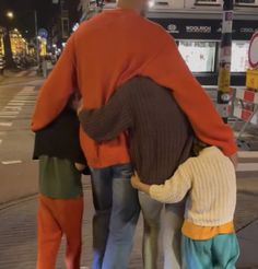 a group of people standing next to each other on a city street at night time