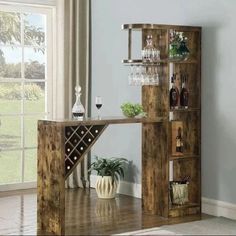 a wooden table with wine glasses and bottles on it in front of a window filled with vases