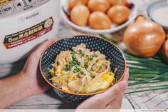 a person holding a bowl of food in front of an instant pot