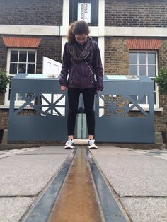 a woman standing on top of a metal object in front of a tall brick building