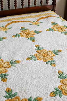 a quilted bedspread with yellow flowers and green leaves on the bottom half