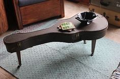 a coffee table with a bowl on it and an old guitar case in the middle