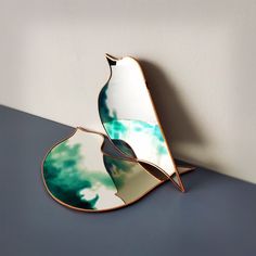 a mirror sitting on top of a black table next to a white and green wall