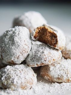 powdered sugar covered doughnuts piled on top of each other in a pile