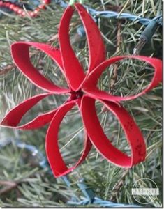 an ornament made out of red paper hanging from a christmas tree with ornaments around it