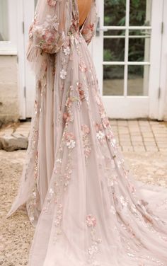 the back of a woman's wedding dress with flowers on it and sheer sleeves