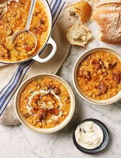 three bowls of soup and bread on a table